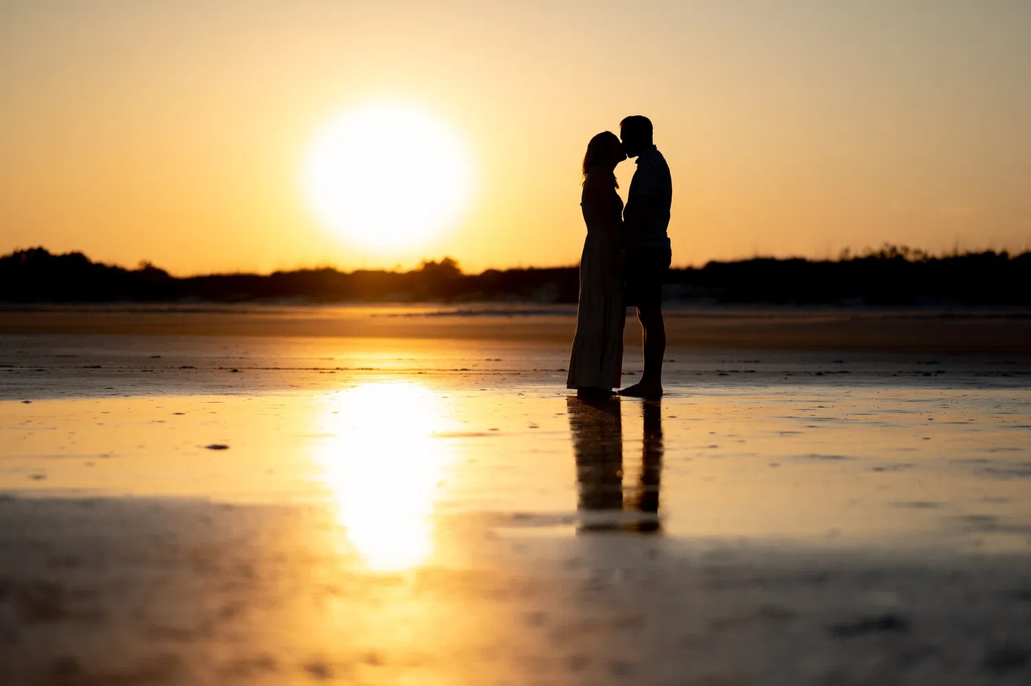 Couple silhouetted against a beach sunset