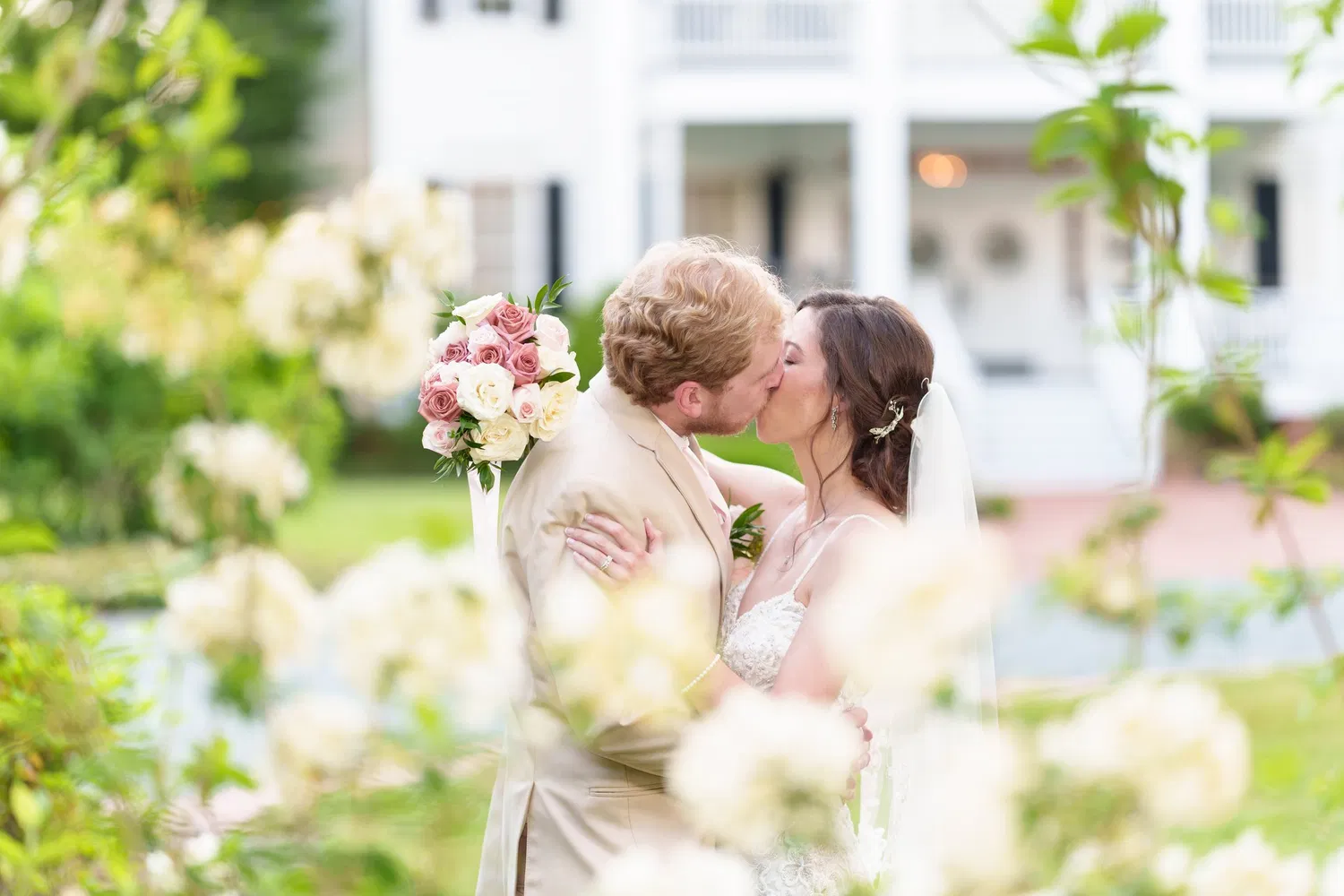 Bride and groom kissing, framed by white flowers, at Tanglewood Plantation